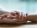 Two people holding hands in a comforting way