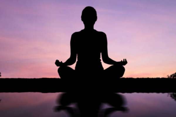 Silhouette of a woman practicing yoga outdoors